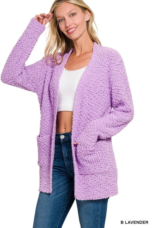 Woman wearing a lavender cardigan with a white top and blue jeans on a white background