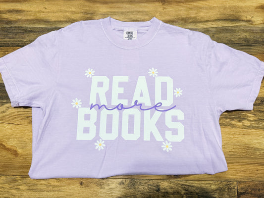 Lavender t-shirt with 'READ more BOOKS' text on a wooden surface