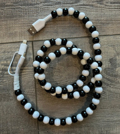 Black and white beaded cable with USB connectors on a wooden surface