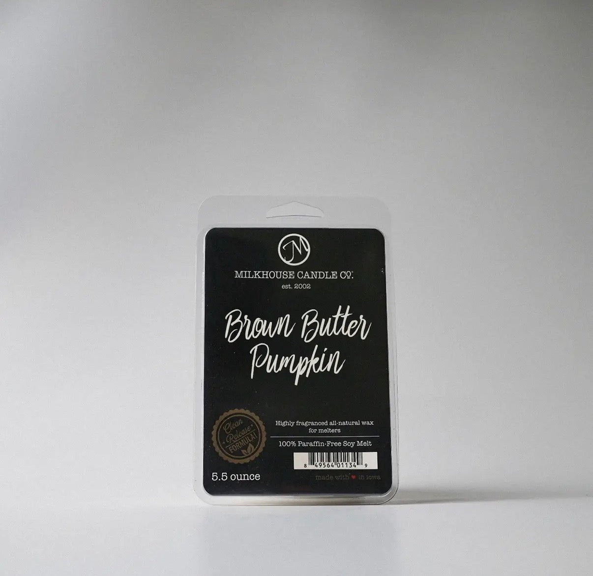 Packaged candle labeled 'Brown Butter Pumpkin' by Milkhouse Candle Co. on a gray background