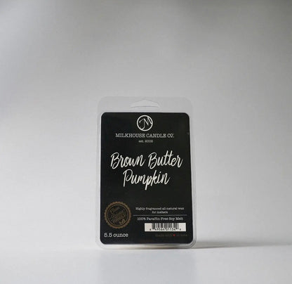 Packaged candle labeled 'Brown Butter Pumpkin' by Milkhouse Candle Co. on a gray background