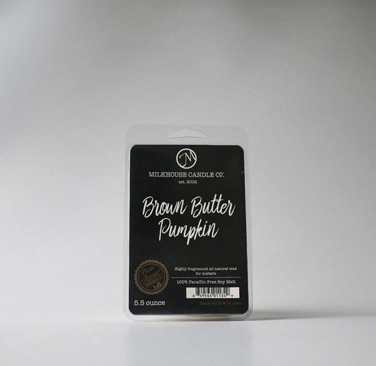 Packaged candle labeled 'Brown Butter Pumpkin' by Milkhouse Candle Co. on a gray background