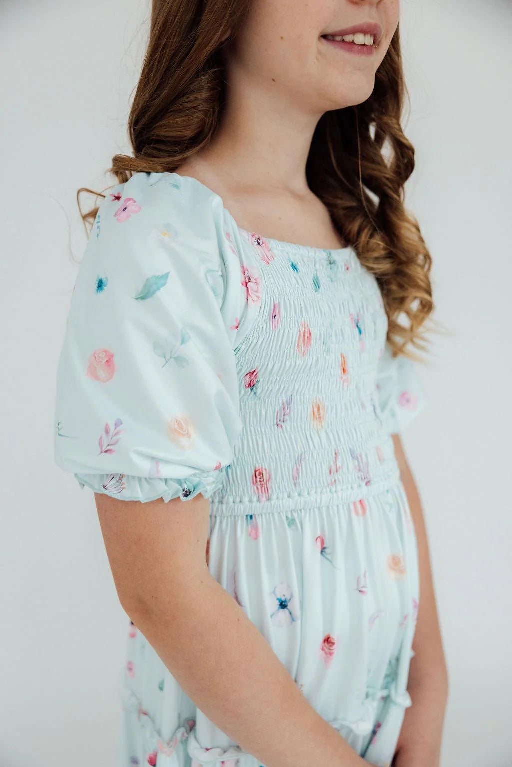 Girl wearing a light blue floral dress against a white background