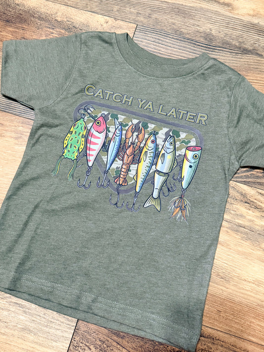 Green t-shirt with fishing lure graphic and 'Catch Ya Later' text on a wooden surface