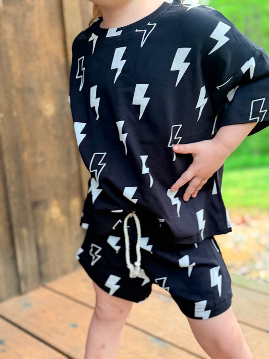 Child wearing a black outfit with white lightning bolt patterns outdoors.