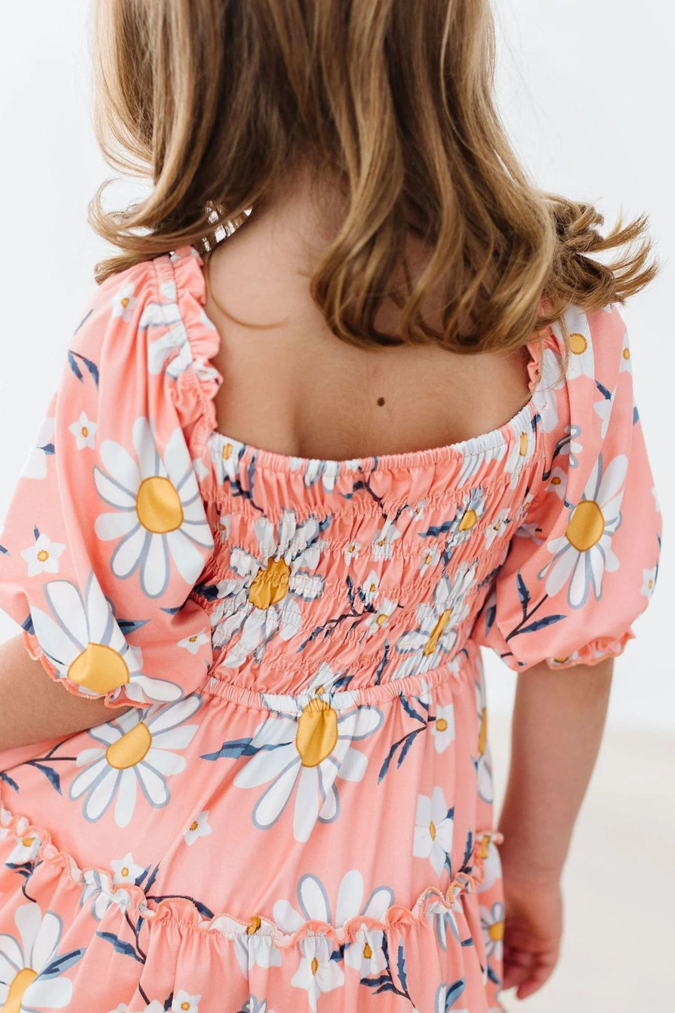Child wearing a pink floral dress with a white background