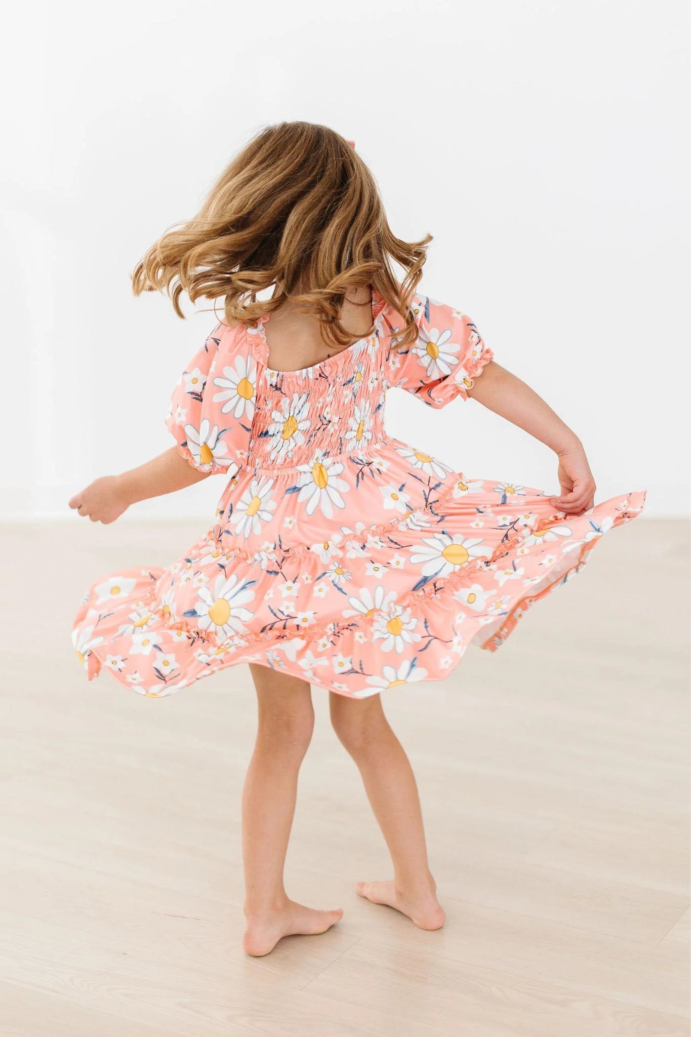 Child wearing a pink floral dress on a plain background