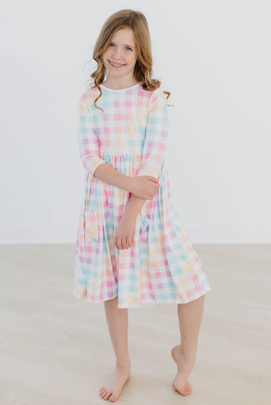 Young girl wearing a pastel plaid dress on a white background