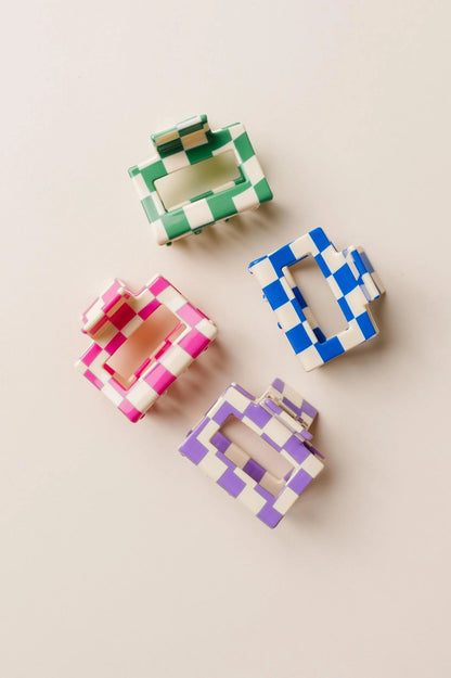 Four colorful checkered hair clips on a beige background
