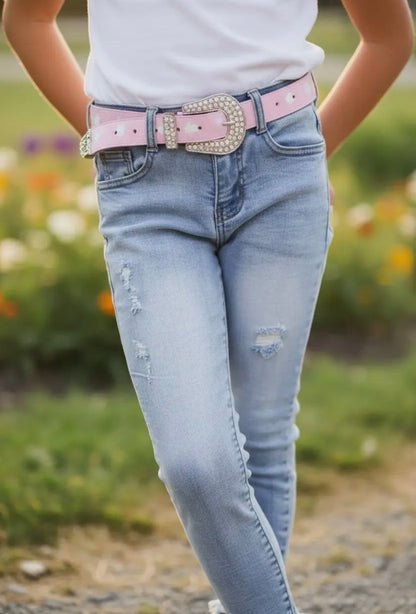 Person wearing light blue jeans with a pink belt and white shirt outdoors.