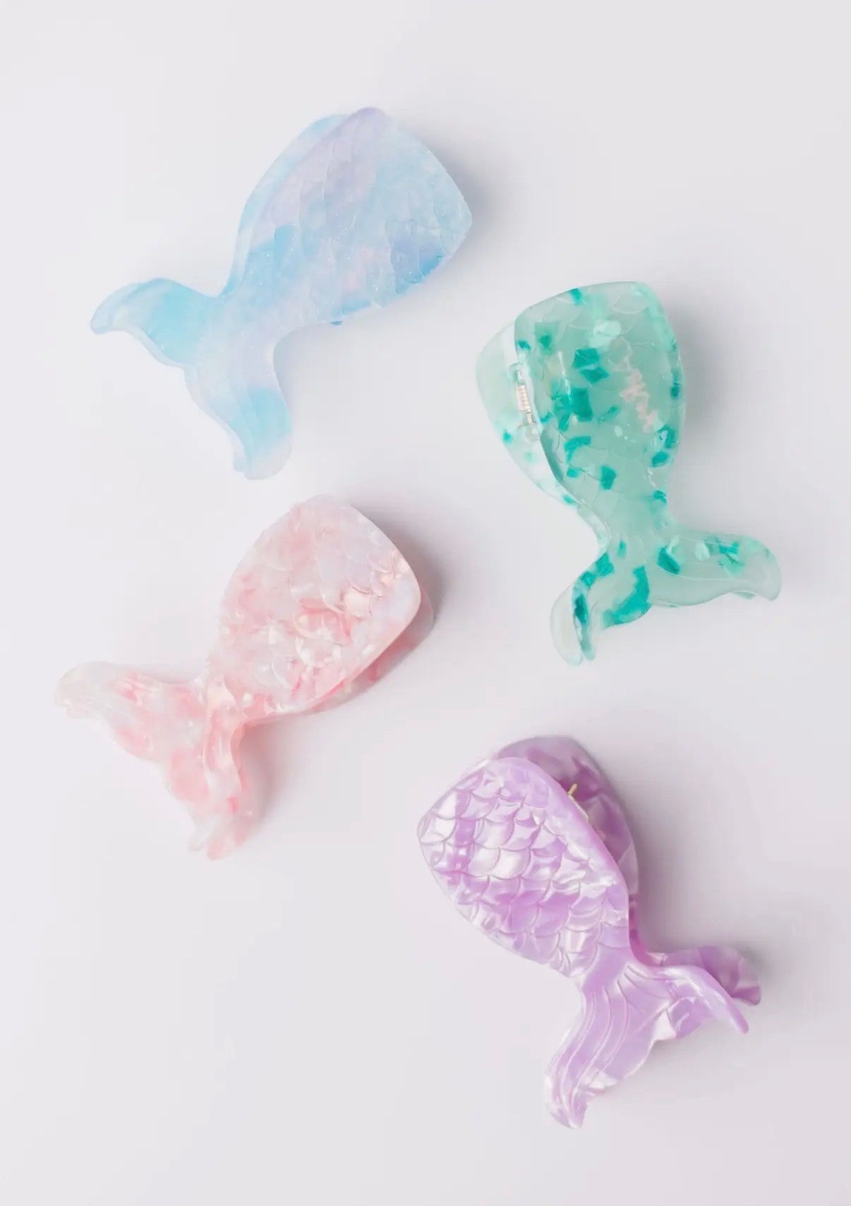 Four colorful mermaid tail claw clips on a white background