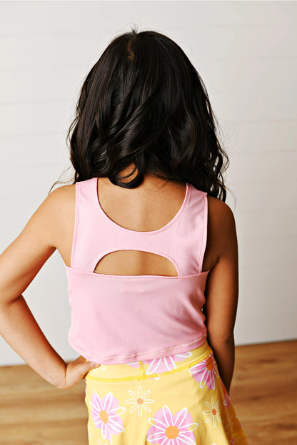 Person wearing a pink tank top with cut-out design and yellow floral skirt.