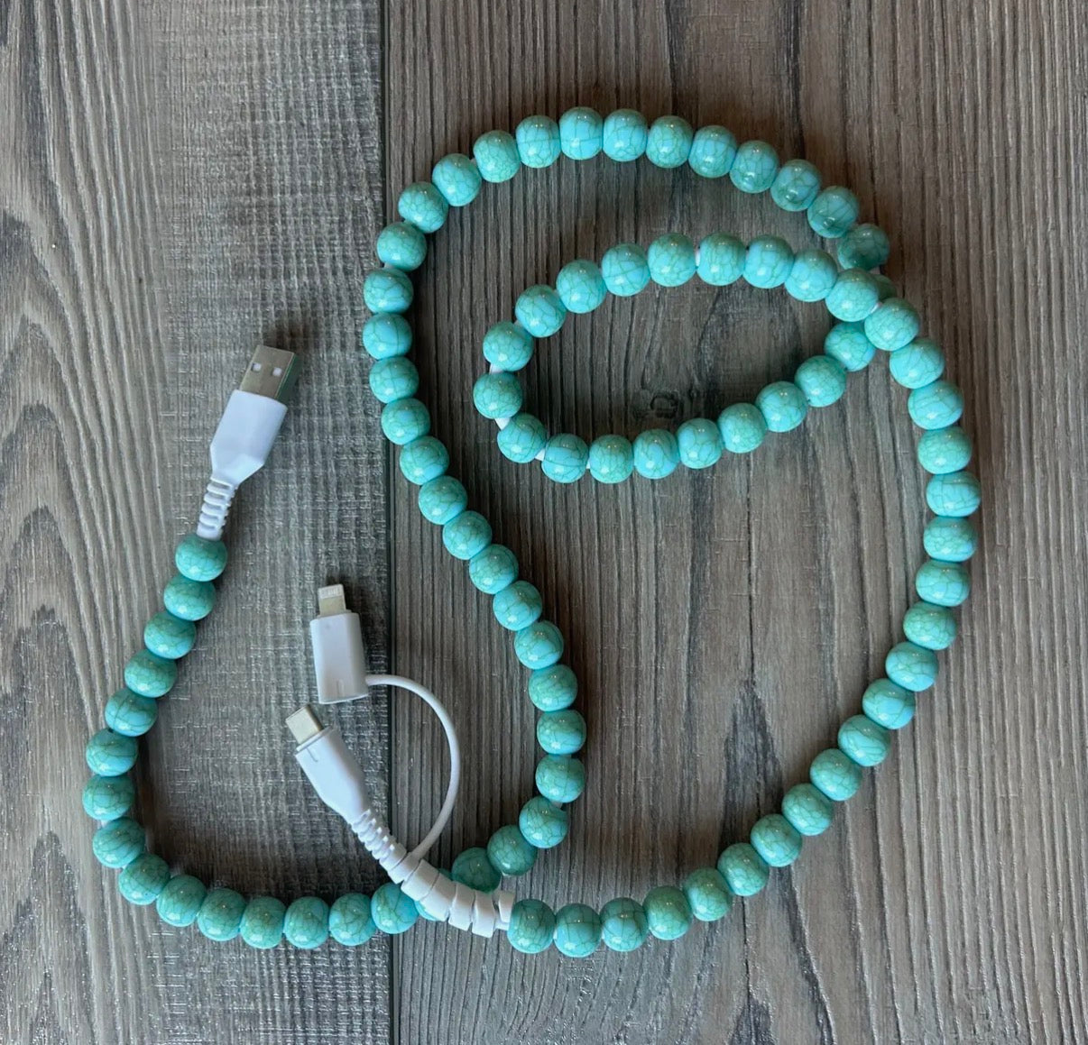 Turquoise beaded cable with USB connectors on a wooden surface