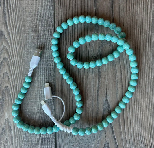 Turquoise beaded cable with USB connectors on a wooden surface