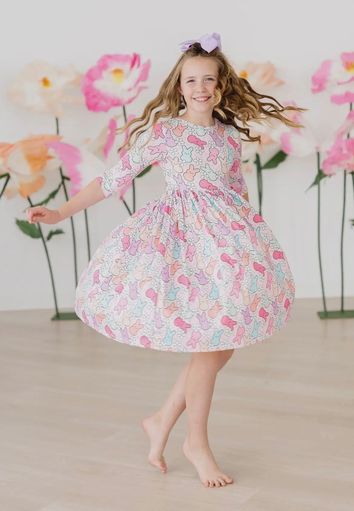 Young girl in a floral dress dancing in front of a floral backdrop