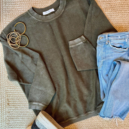 Hunter green corded crew and blue jeans on a textured surface