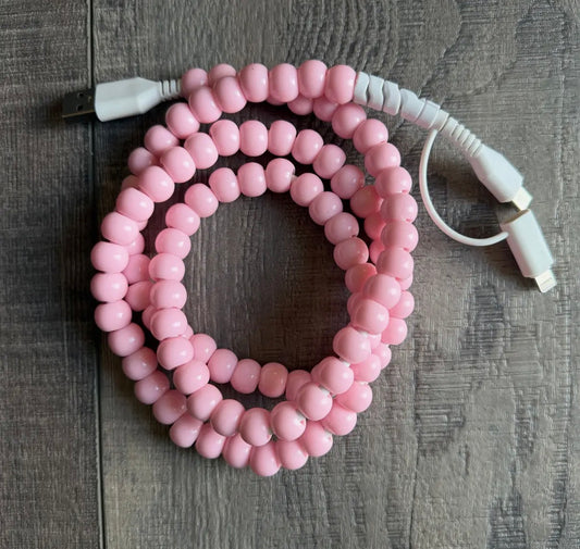 Pink beaded charger with white connectors on a wooden surface