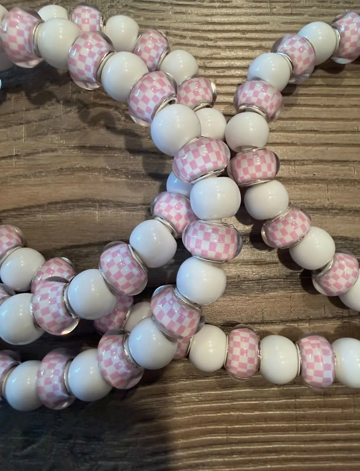 Beaded charger with pink and white checkered beads on a wooden surface