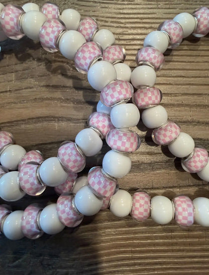 Beaded charger with pink and white checkered beads on a wooden surface