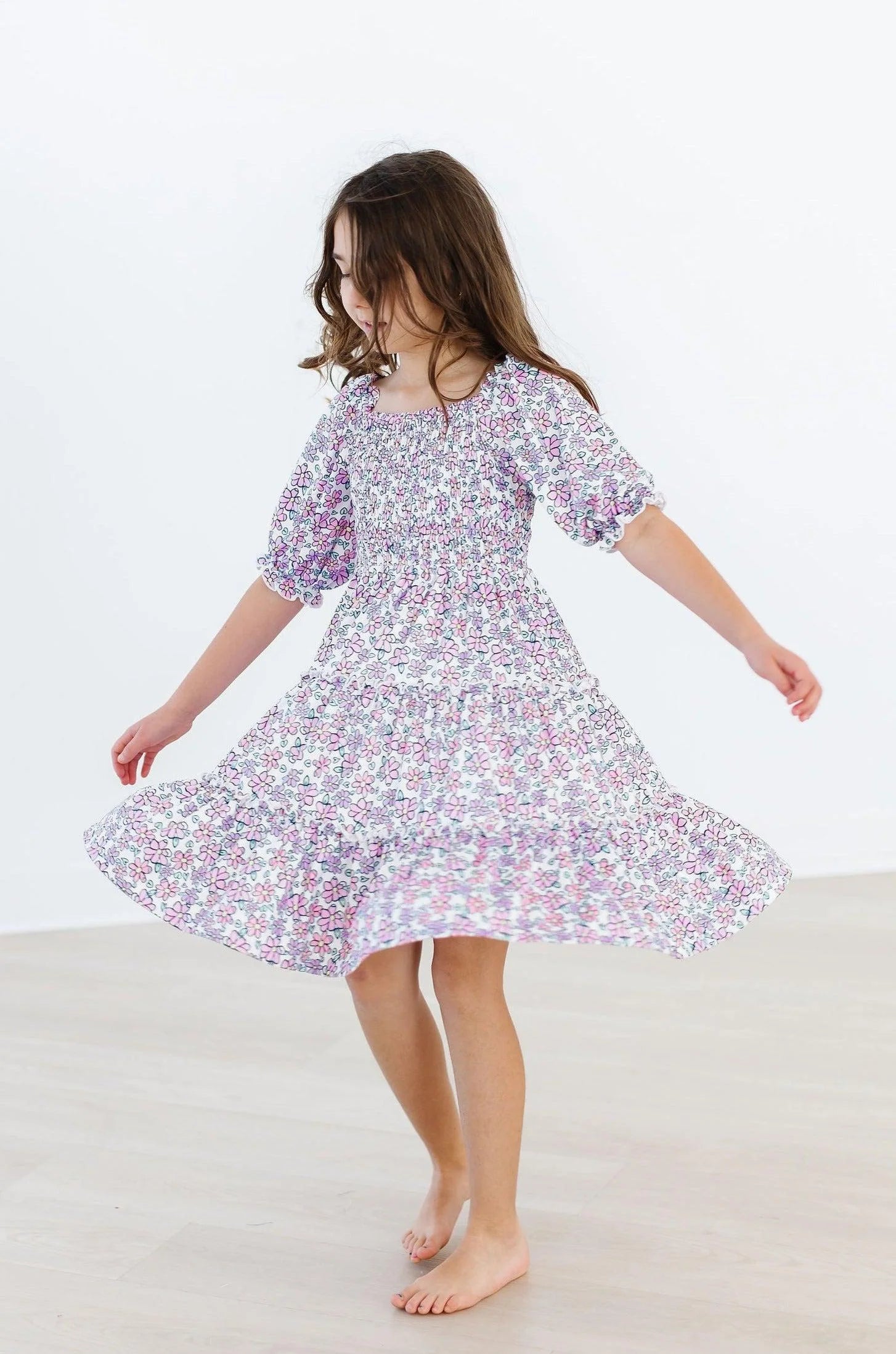 Young girl wearing a lavender floral dress on a plain background