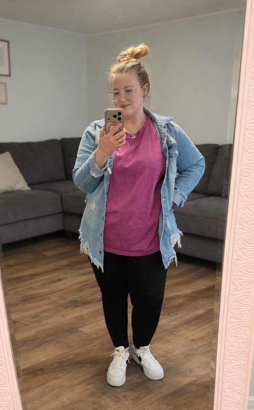 Person taking a mirror selfie wearing a plum shirt, black pants, and a light blue denim jacket in a living room.