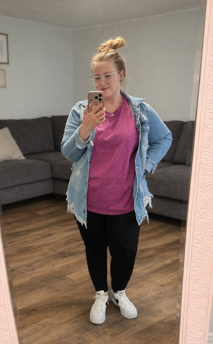 Person taking a mirror selfie wearing a plum shirt, black pants, and a light blue denim jacket in a living room.