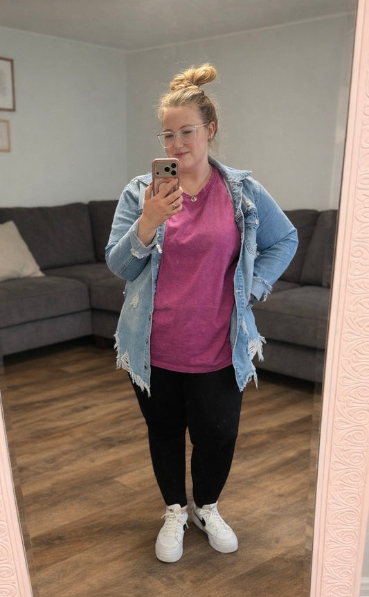 Person taking a mirror selfie wearing a plum shirt, black pants, and a light blue denim jacket in a living room.
