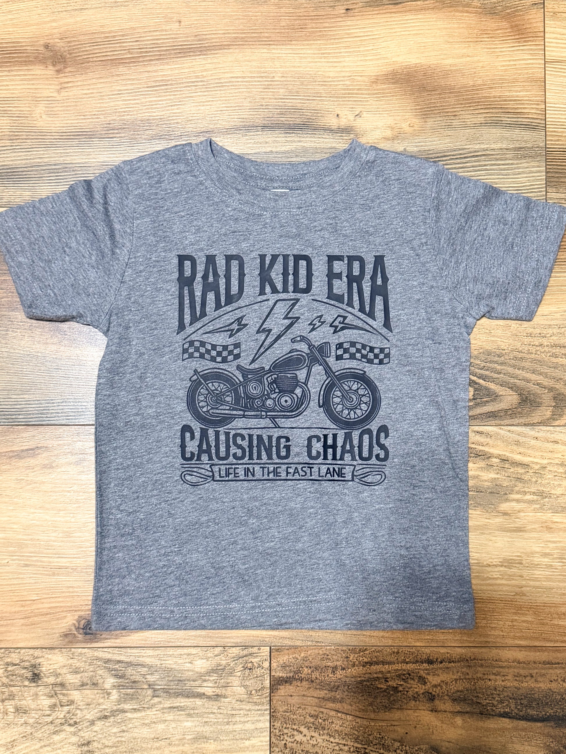 Gray t-shirt with motorcycle graphic and text on a wooden surface