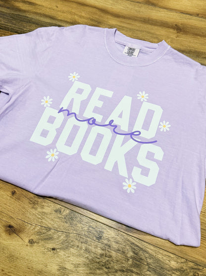 Lavender t-shirt with 'Read more books' text on a wooden surface