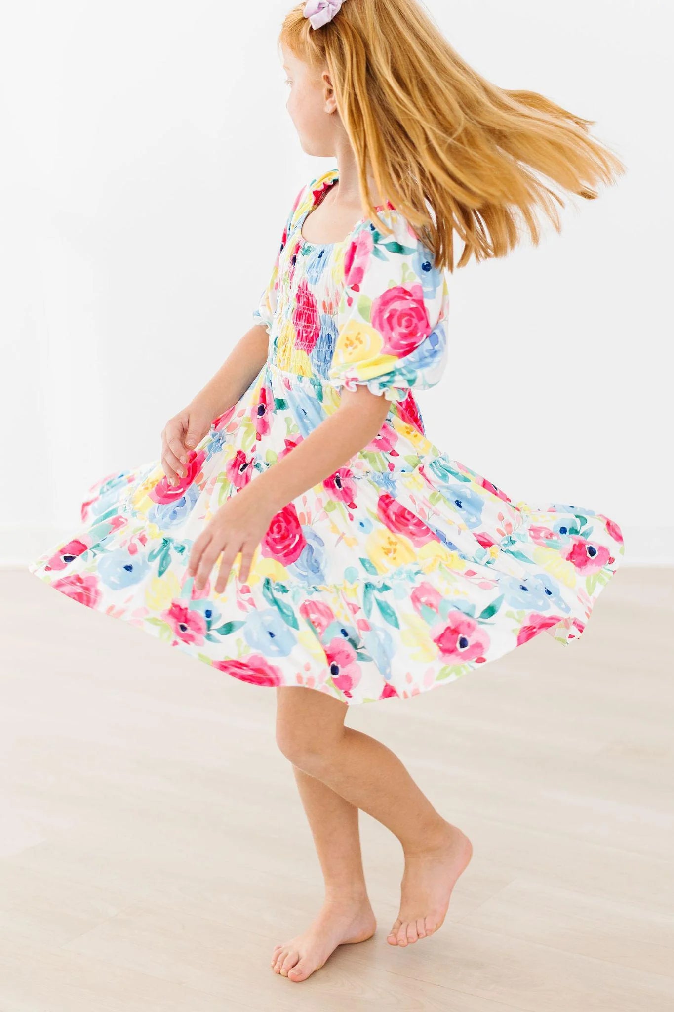Young girl wearing a colorful floral dress on a plain background