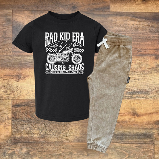 Black t-shirt with graphic design and tan joggers on a wooden surface