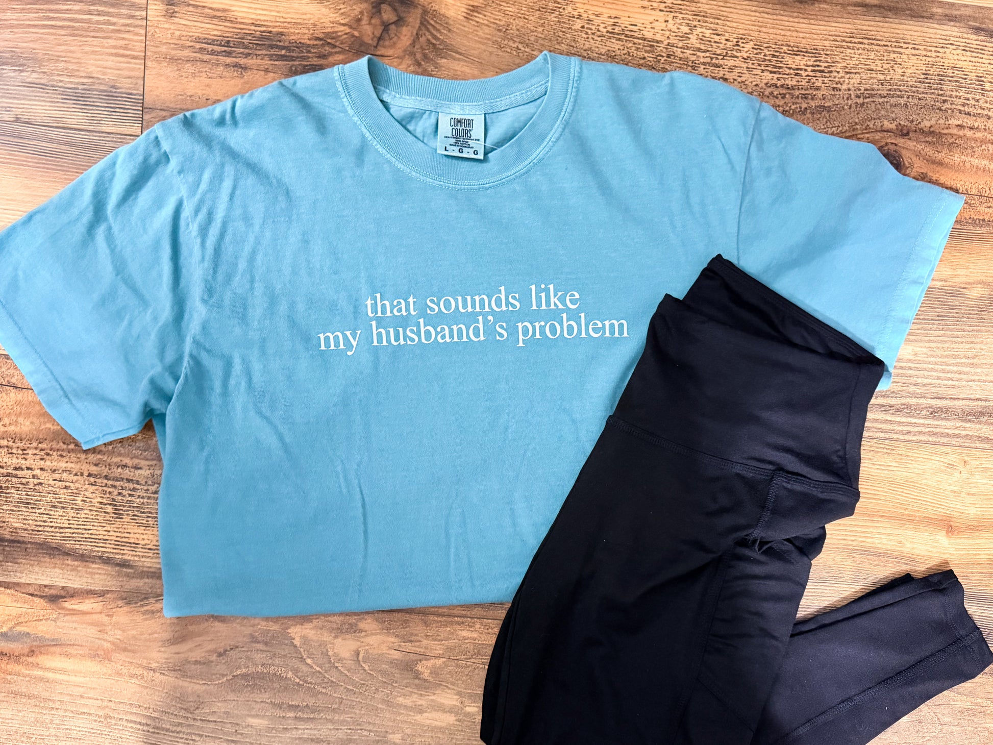 Blue t-shirt with text and black leggings on a wooden surface