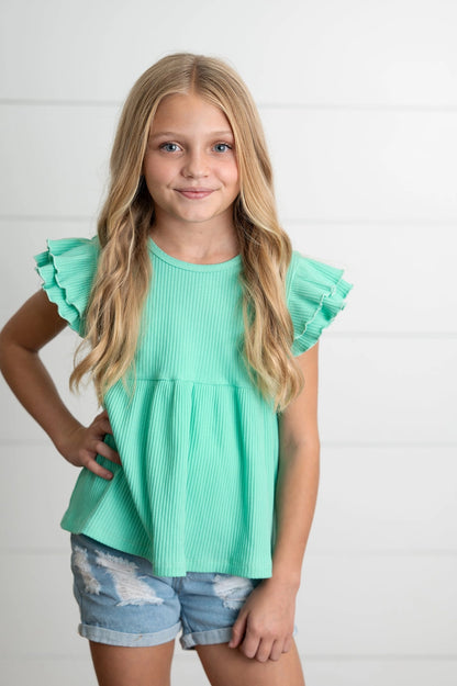 Young girl wearing a turquoise top with ruffled sleeves on a white background