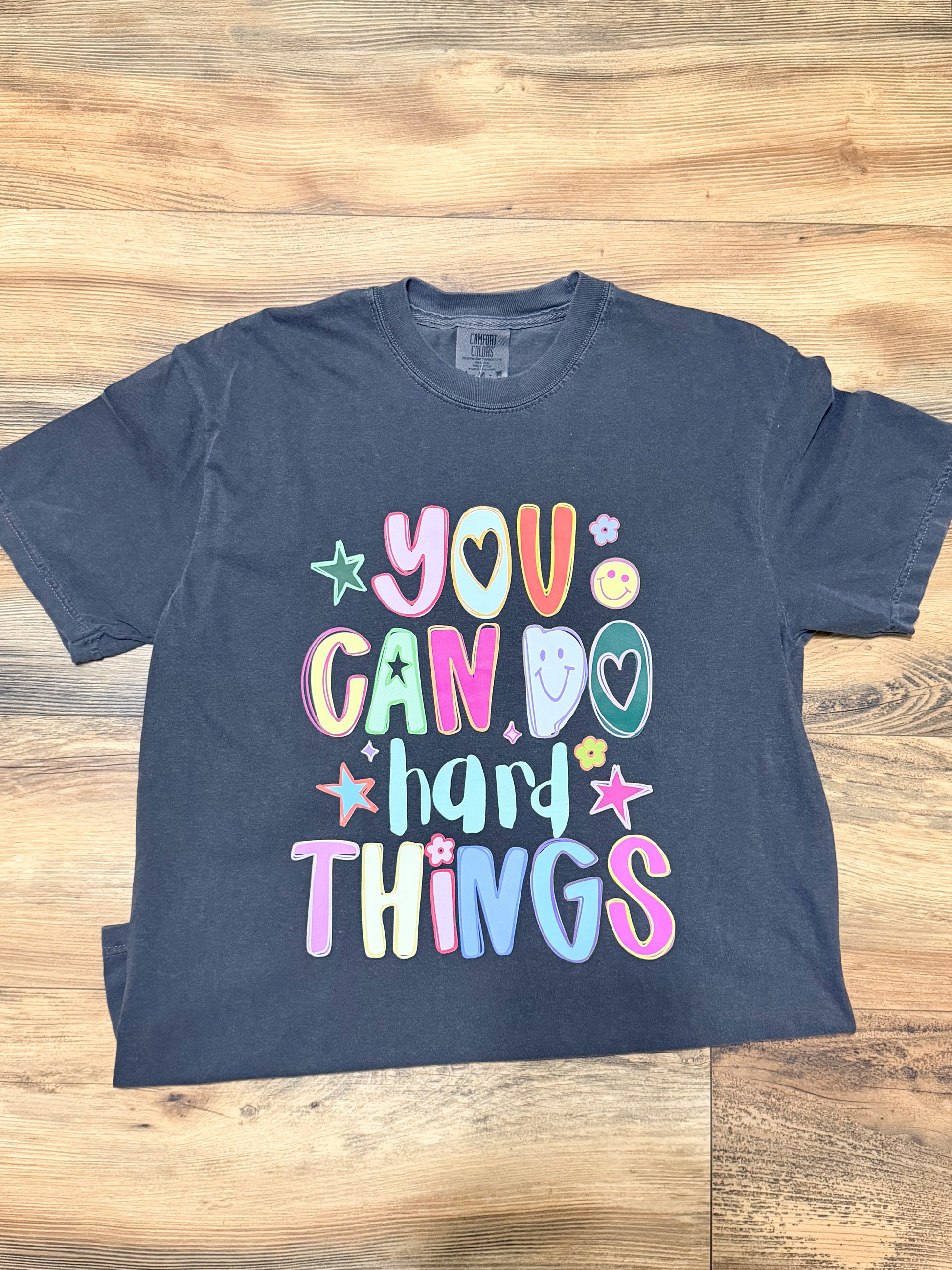 Pepper grey t-shirt with colorful text on a wooden surface