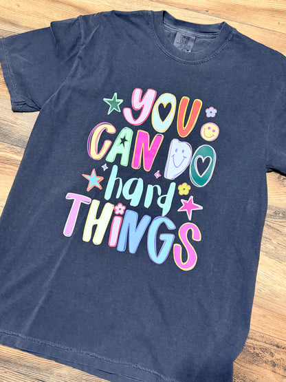 Pepper grey t-shirt with colorful text and graphics on a wooden surface